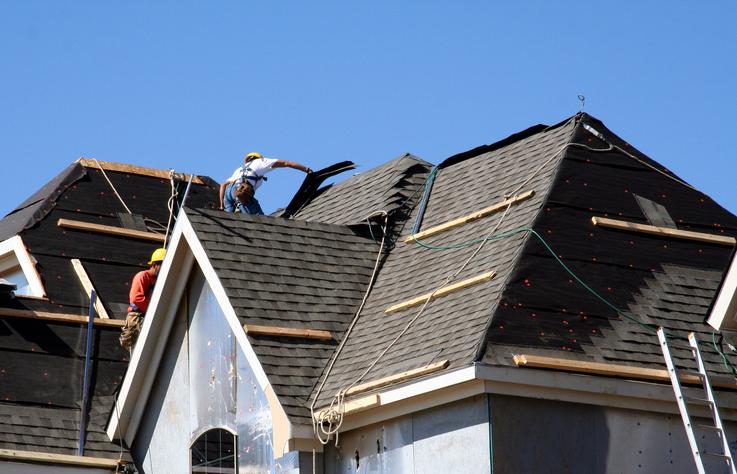 建筑工人在屋顶上盖木瓦.